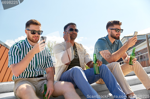 Image of men with smartphones drinking beer on street