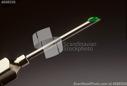 Image of Drop of green liquid at the tip of a hypodermic needle