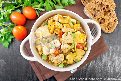 Image of Chicken with vegetables and peas in saucepan on board top