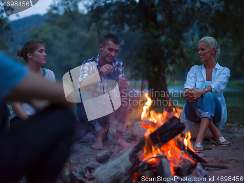 Image of young friends relaxing around campfire