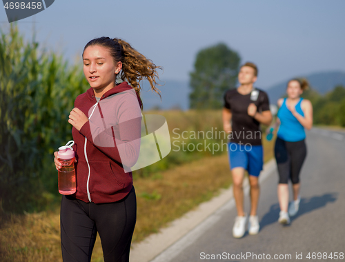 Image of young people jogging on country road