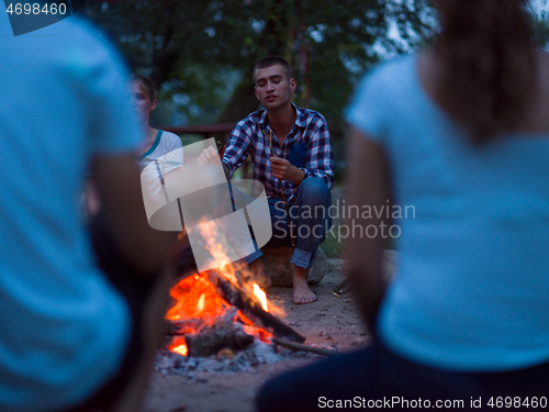 Image of young friends relaxing around campfire