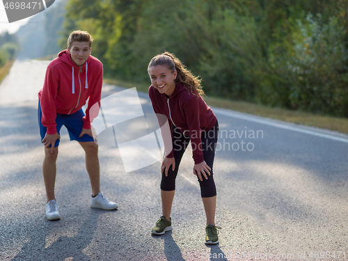 Image of young couple warming up and stretching on a country road