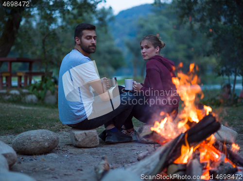 Image of couple sitting around the campfire at evening