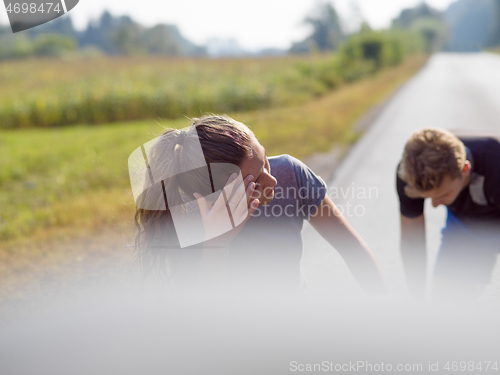 Image of young couple warming up and stretching on a country road