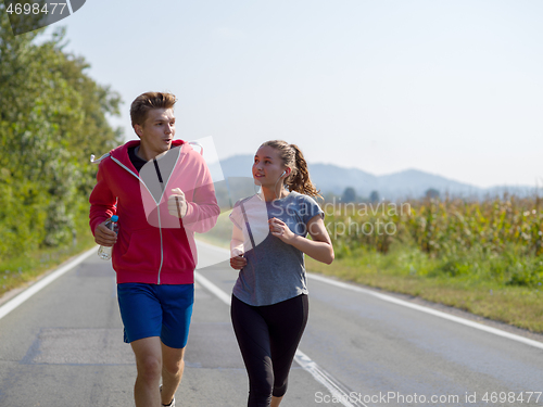 Image of young couple jogging along a country road