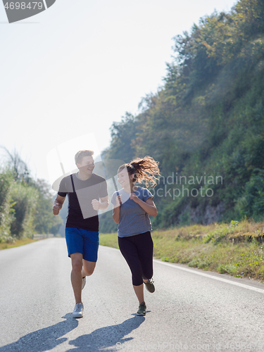 Image of young couple jogging along a country road