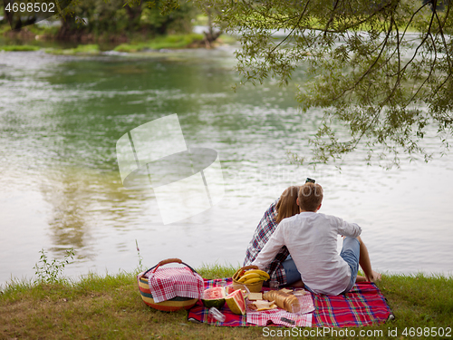 Image of Couple taking a selfie by mobile phone while enjoying picnic tim