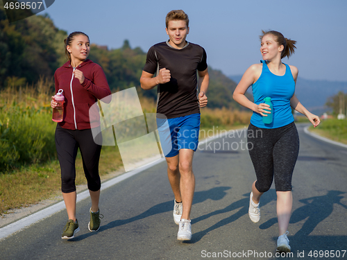 Image of young people jogging on country road