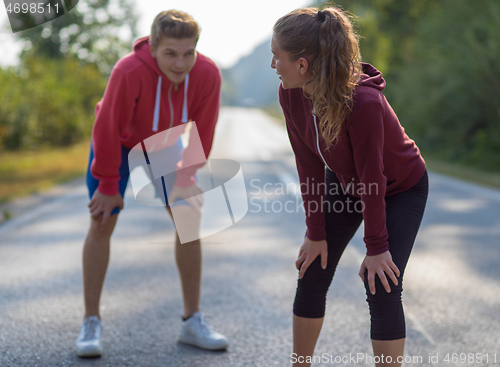 Image of young couple warming up and stretching on a country road