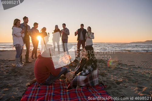 Image of Couple enjoying with friends at sunset on the beach