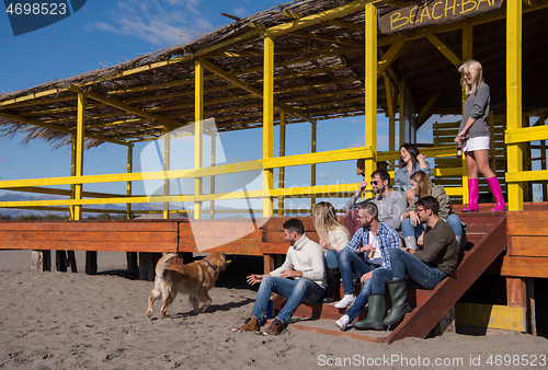Image of Group of friends having fun on autumn day at beach