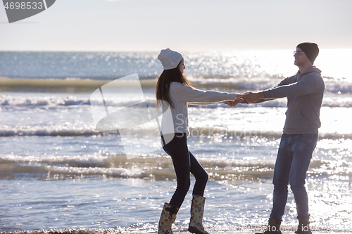 Image of Loving young couple on a beach at autumn sunny day