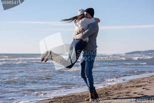 Image of Loving young couple on a beach at autumn sunny day