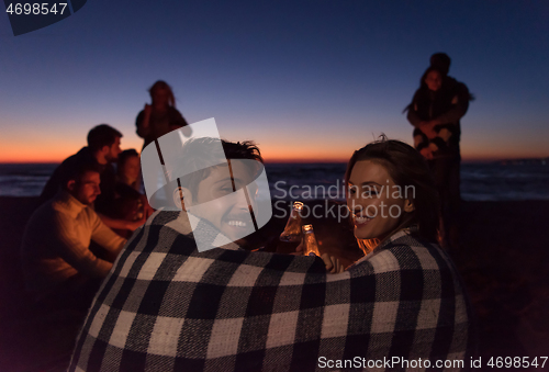 Image of Couple enjoying with friends at sunset on the beach