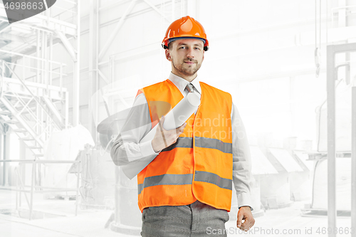 Image of The builder in orange helmet against industrial background