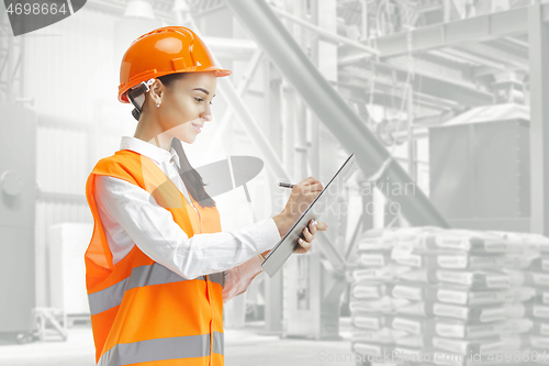 Image of Destroying gender stereotypes. Female builder standing against industrial background