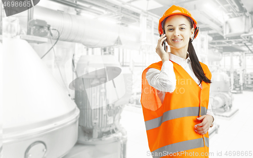 Image of Destroying gender stereotypes. Female builder standing against industrial background