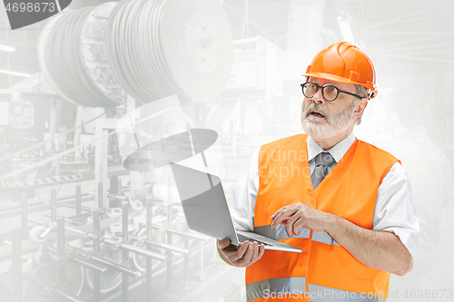 Image of The builder in orange helmet against industrial background