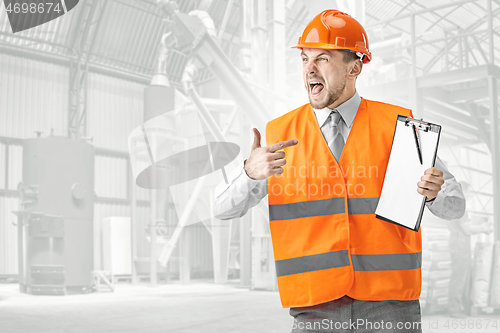 Image of The builder in orange helmet against industrial background