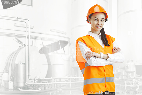Image of Destroying gender stereotypes. Female builder standing against industrial background