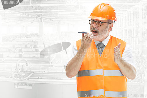 Image of The builder in orange helmet against industrial background