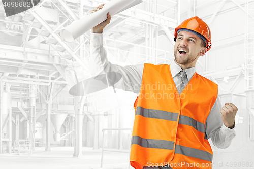 Image of The builder in orange helmet against industrial background