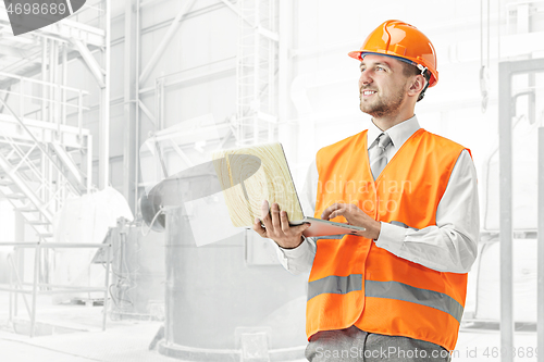 Image of The builder in orange helmet against industrial background