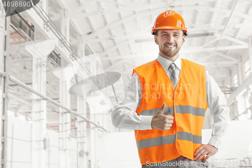 Image of The builder in orange helmet against industrial background