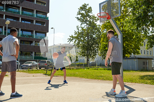 Image of group of male friends playing street basketball