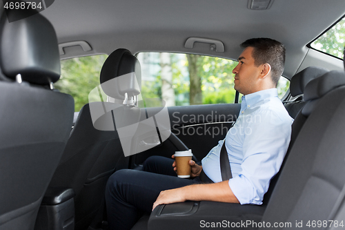 Image of businessman with takeaway coffee on car back seat