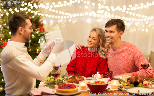 Image of happy friends photographing at christmas dinner