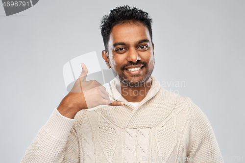 Image of indian man in knitted sweater over gray background