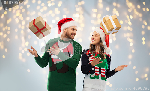 Image of happy couple in ugly sweaters with christmas gifts