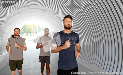 Image of male friends with headphones running outdoors