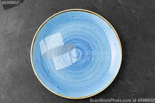 Image of close up of blue ceramic plate on slate background