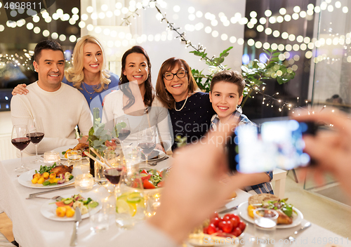 Image of family photographing by smartphone at dinner party