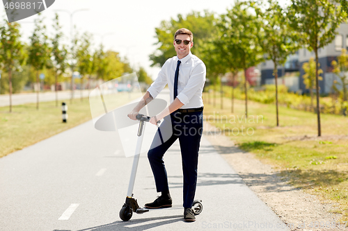 Image of young businessman riding electric scooter in city