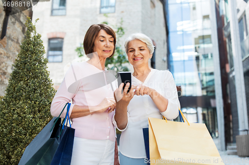 Image of old women with shopping bags and cellphone in city