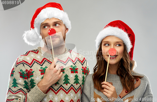 Image of couple with christmas party props in ugly sweaters