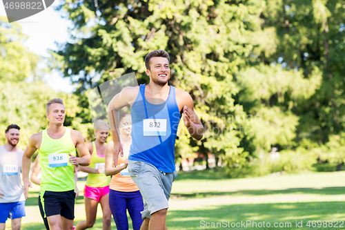 Image of happy young sportsmen racing wit badge numbers