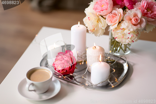 Image of coffee, candles, garland and flowers on table