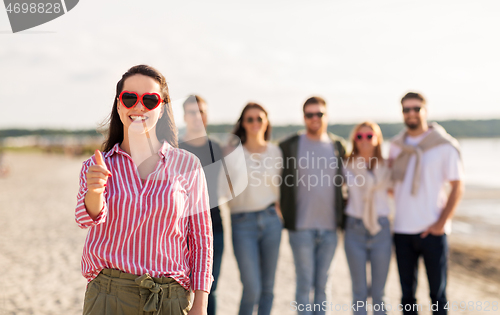 Image of woman with friends on beach showing thumbs up