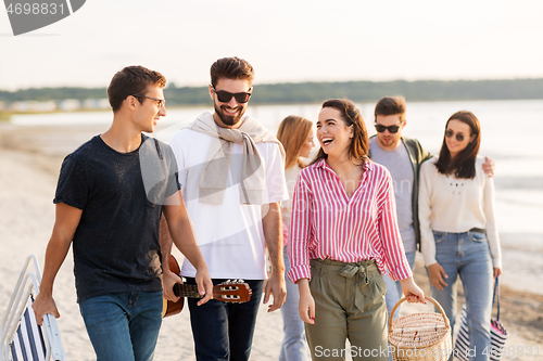 Image of happy friends walking along summer beach