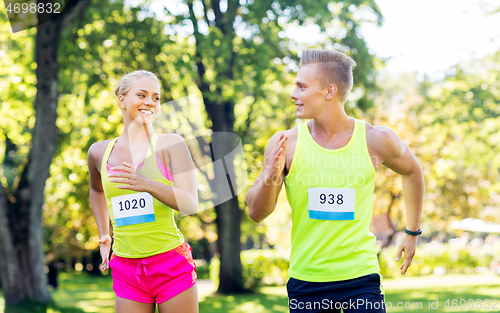 Image of happy couple of sportsmen racing wit badge numbers