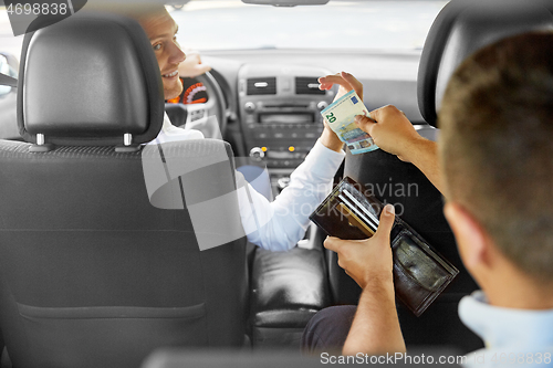 Image of male car driver taking money from passenger