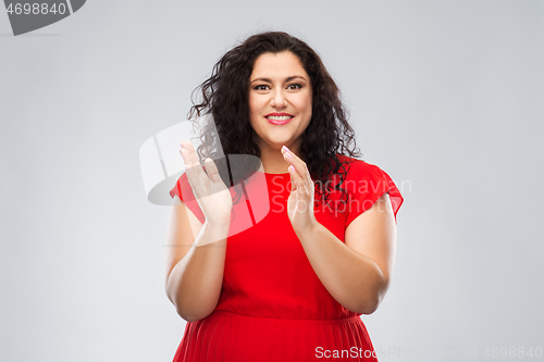 Image of happy woman in red dress applauding