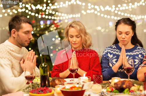 Image of friends praying before christmas dinner at home
