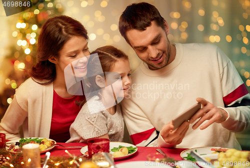 Image of family with smartphone having christmas dinner