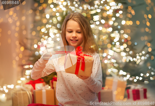 Image of smiling girl with christmas gift at home
